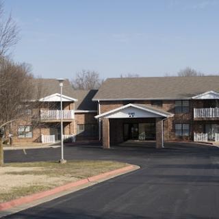 A view of a residential apartment complex with a main entrance and surrounding outdoor area.