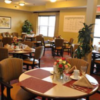 A cozy dining room with neatly arranged tables and chairs, decorated with flowers and placemats.