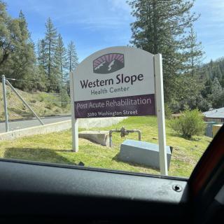 A roadside sign for the Western Slope Recovery Center, surrounded by trees.