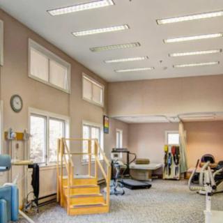 A spacious rehabilitation room with various exercise equipment and facilities for physical therapy.