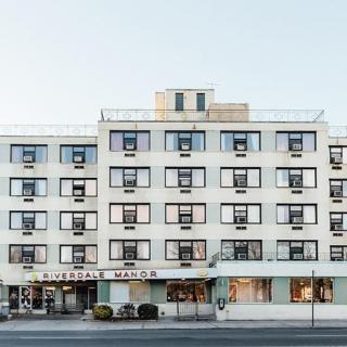 A view of a multi-story city hotel with numerous windows and a street-level entrance.