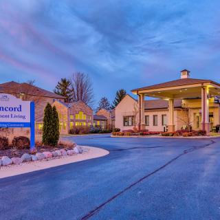 Entrance of a residential building with illuminated signage and driveway during the evening.