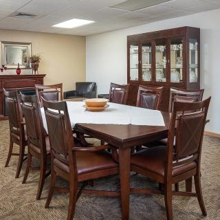 A well-furnished dining room with a large table, several chairs, and a cabinet in the background.