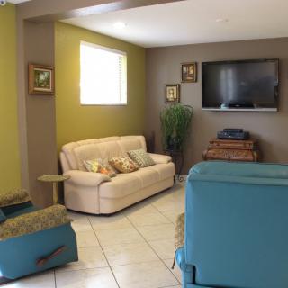 A cozy living room featuring a beige sofa, a blue armchair, and a mounted television.