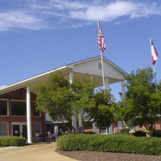 A modern building with an American and another flag, surrounded by trees under a clear sky.