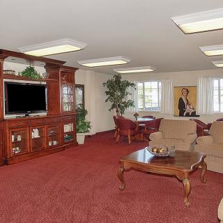 A spacious living room with classic wooden furniture, a large television, and comfortable seating.