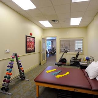 A well-equipped physical therapy room with a therapy table and exercise equipment.