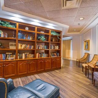A cozy library space featuring a large wooden bookshelf and comfortable seating.