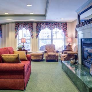 A cozy living room with a red sofa, fireplace, and elegant drapery.