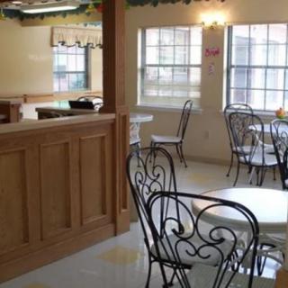 An empty cafe with wrought iron chairs and wooden decor, illuminated by natural light from large windows.