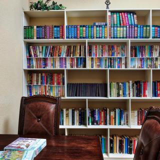 A cozy reading room with a well-organized bookshelf and comfortable chairs.