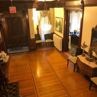 A classic hallway with wooden flooring, a chandelier, and antique furnishings.