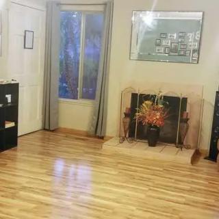 A cozy living room with hardwood flooring, a fireplace, and large windows.