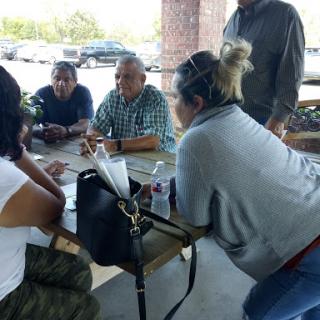 A group of people engaged in a discussion at an outdoor table.