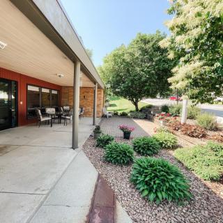 A peaceful patio area with outdoor seating and well-maintained landscaping on a sunny day.