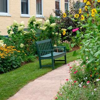 A peaceful garden with a bench surrounded by colorful flowers and a pathway.