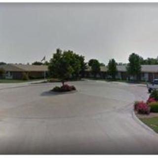 A peaceful outdoor area featuring a parking lot surrounded by greenery and a central tree.