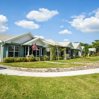 A row of houses with well-maintained lawns and a clear sky above.