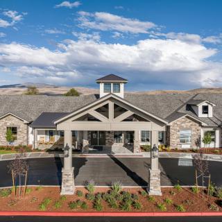 A beautiful residential building with a welcoming entrance set against a backdrop of clouds and mountains.