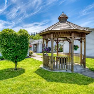 A wooden gazebo in a well-maintained garden on a sunny day.