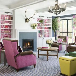 A vibrant living room with colorful armchairs and a central fireplace, featuring a cozy and eclectic design.