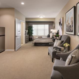 A modern living space featuring a comfortable seating area and a bed, with stylish decor and soft lighting.
