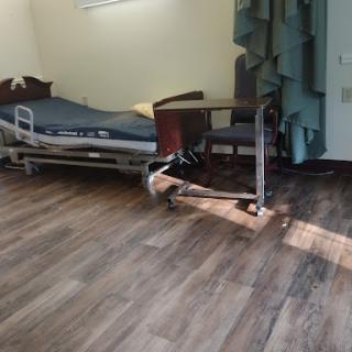 A hospital room featuring a bed, furniture, and natural light.