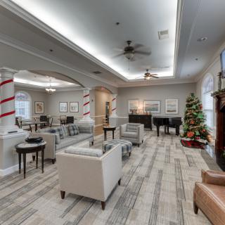 A modern lounge area decorated with a Christmas tree and festive ornaments, featuring comfortable seating and elegant lighting.