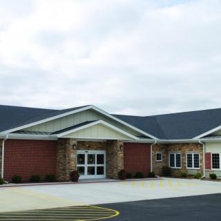 A modern building with a brick exterior and a spacious parking area.