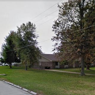 A quiet suburban house surrounded by trees and a well-kept lawn.
