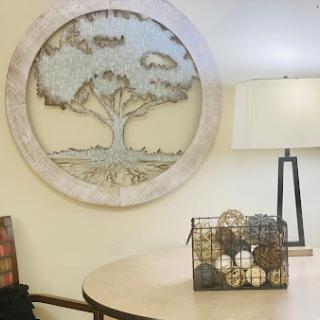 A beautifully designed wall art featuring a tree, complemented by a stylish lamp and decorative items on the table.