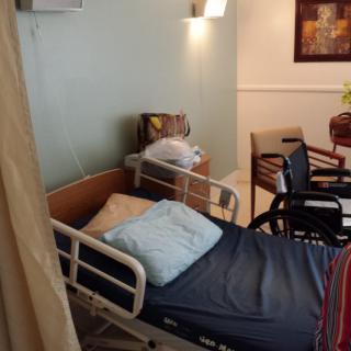 A healthcare room with a hospital bed and wheelchair.