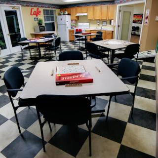 A cozy kitchen and dining area with tables and chairs, featuring a checkered floor.