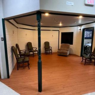 An indoor room with several chairs arranged in a semi-circle on a wooden floor.
