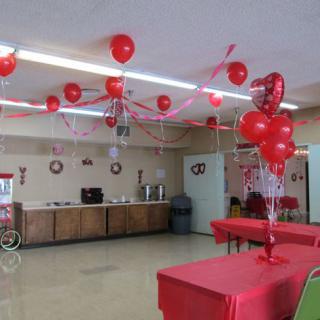 A room decorated with red balloons and tablecloths, set up for a party or event.
