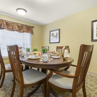 A cozy dining room with a round wooden table set for a meal.