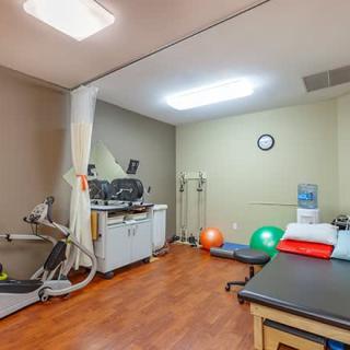 A physical therapy clinic with exercise equipment and treatment tables.
