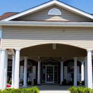 A front view of a building entrance featuring white columns and a peaked roof.