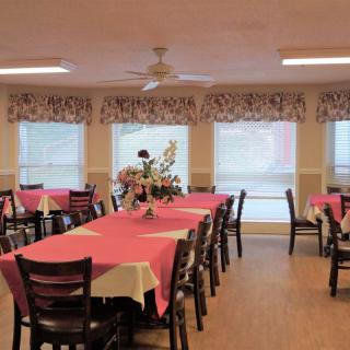 A dining area with tables covered in pink tablecloths, surrounded by chairs and decorated with floral centerpieces.
