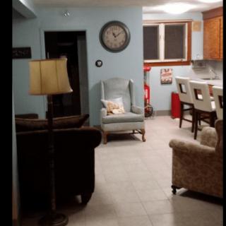 A cozy living room with a view into the kitchen, featuring comfortable seating and homey decor.