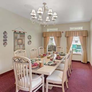 A classic dining room setup with a long table, surrounded by chairs and adorned with a chandelier.