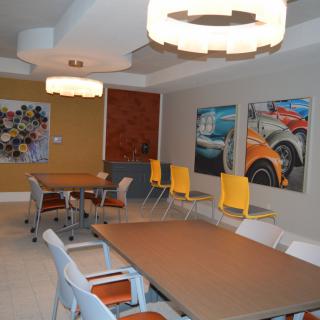A modern meeting room with colorful chairs, tables, and wall art.