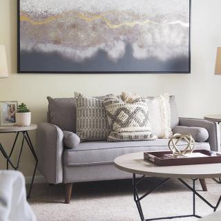 A cozy living room with a grey sofa, decorative pillows, and modern artwork.