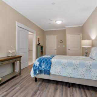 A modern bedroom with a neatly made bed, hardwood flooring, and subtle neutral decor.