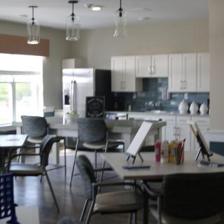 A modern kitchen and dining area with tables and chairs, featuring bright lighting and sleek design.