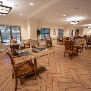 A spacious and elegantly decorated dining area with wooden floors and well-arranged tables.