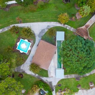 Aerial view of a property featuring a house, swimming pool, and landscaped garden.