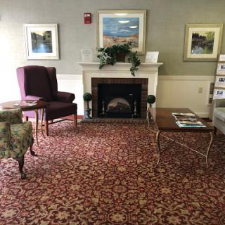 A cozy lobby area featuring comfortable seating, a decorative fireplace, and elegant artwork.