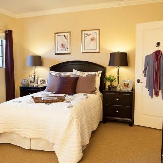 A cozy bedroom with a neatly made bed, two bedside tables with lamps, and framed pictures on the wall.