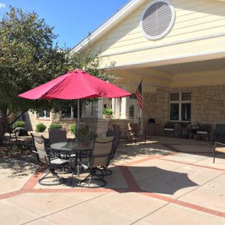 A cozy outdoor patio with a red umbrella, perfect for enjoying a sunny day.